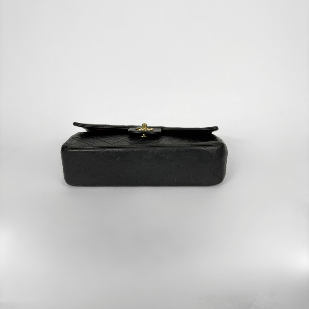 Black quilted Chanel shoulder bag with gold hardware on a white background