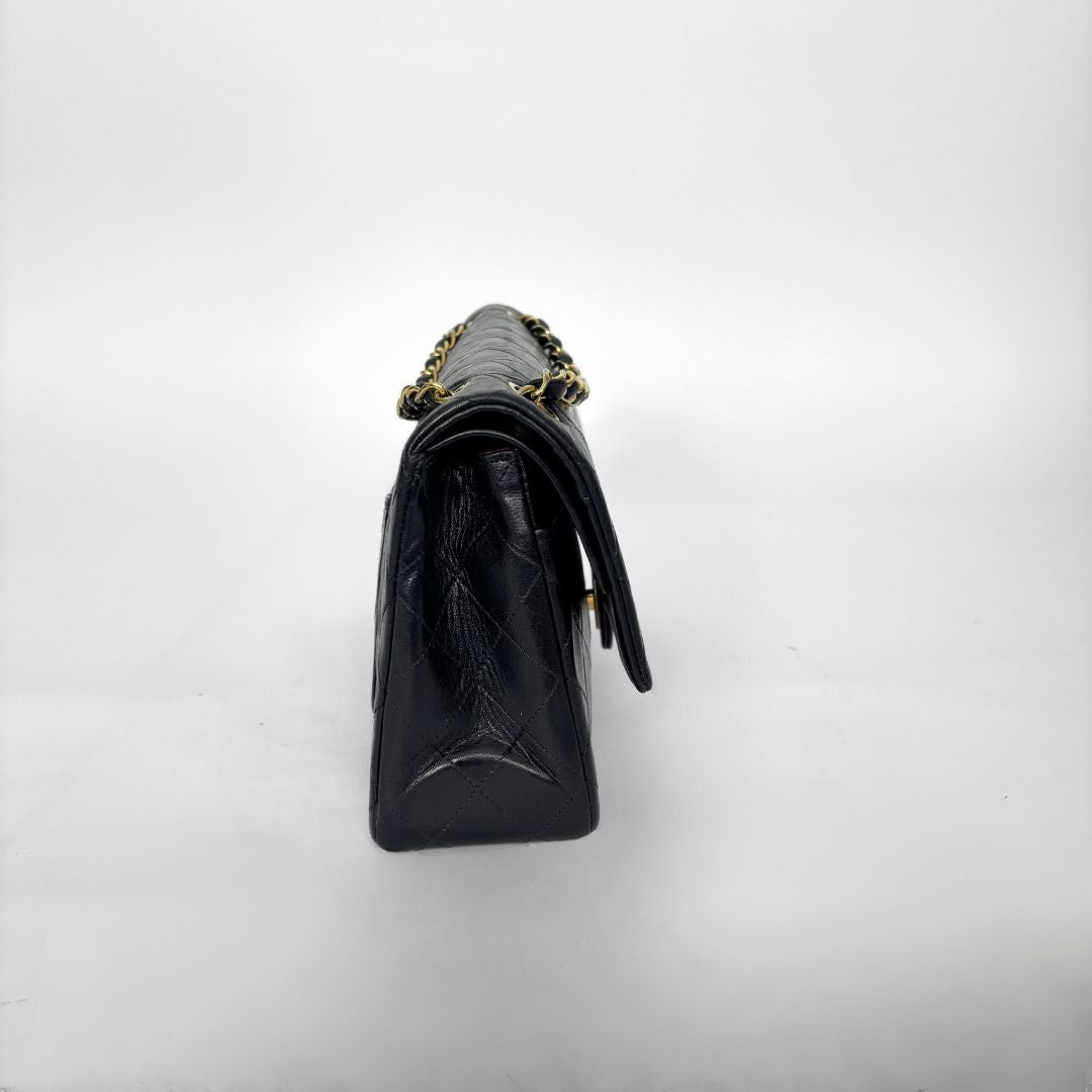 Black handbag with gold chain strap on a white background