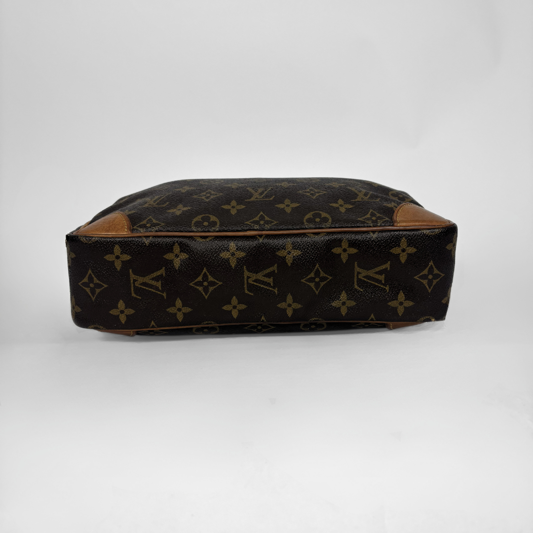 Louis Vuitton monogram canvas bag shown from the bottom corner, featuring the classic brown and gold monogram pattern with tan leather trim on a white background.