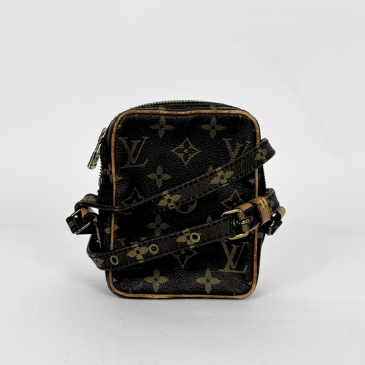 Bolsa preta com monograma dourado sobre fundo branco.
