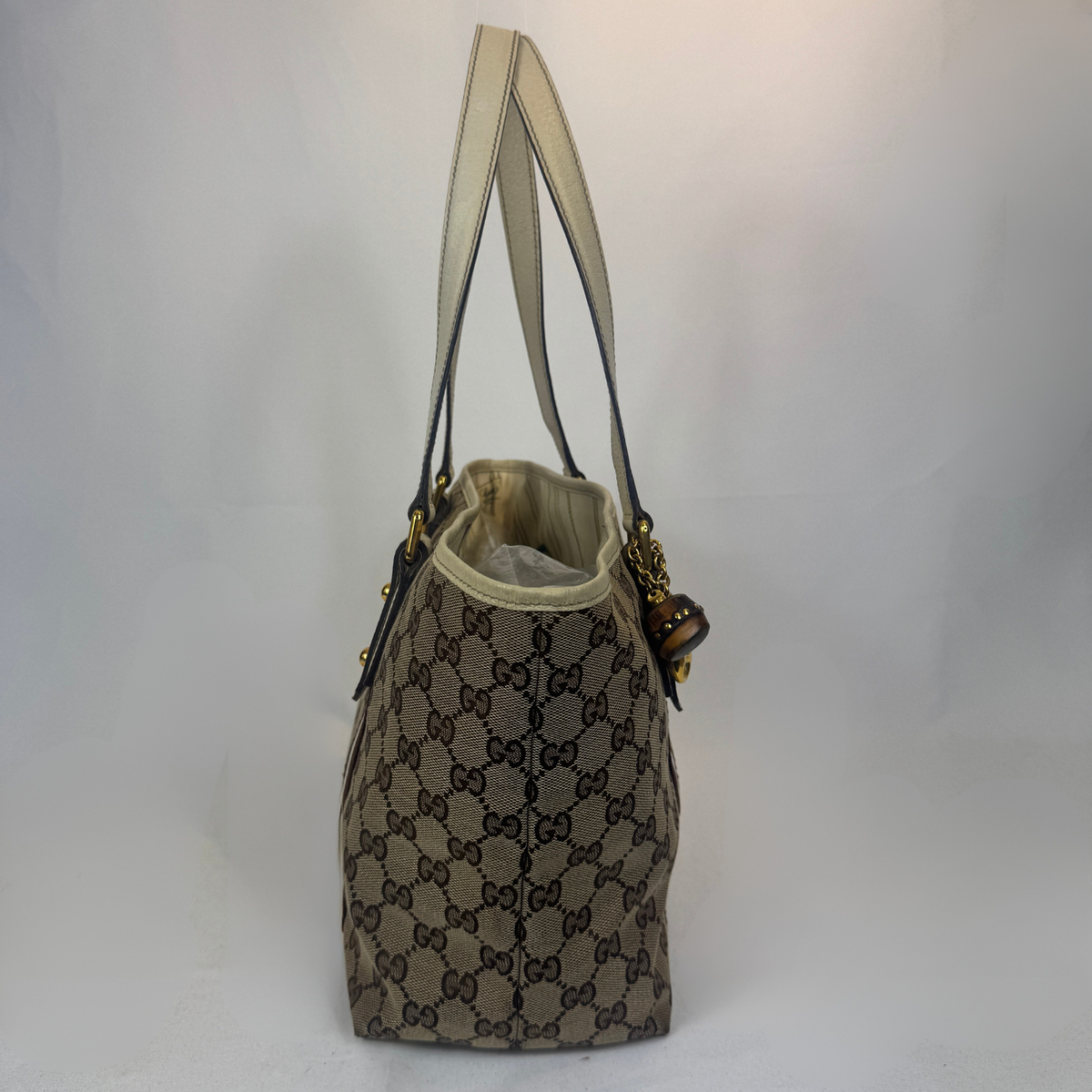 A vintage Gucci tote bag in brown and beige GG Supreme canvas with beige leather shoulder straps and gold-tone hardware, shown against a plain white background.