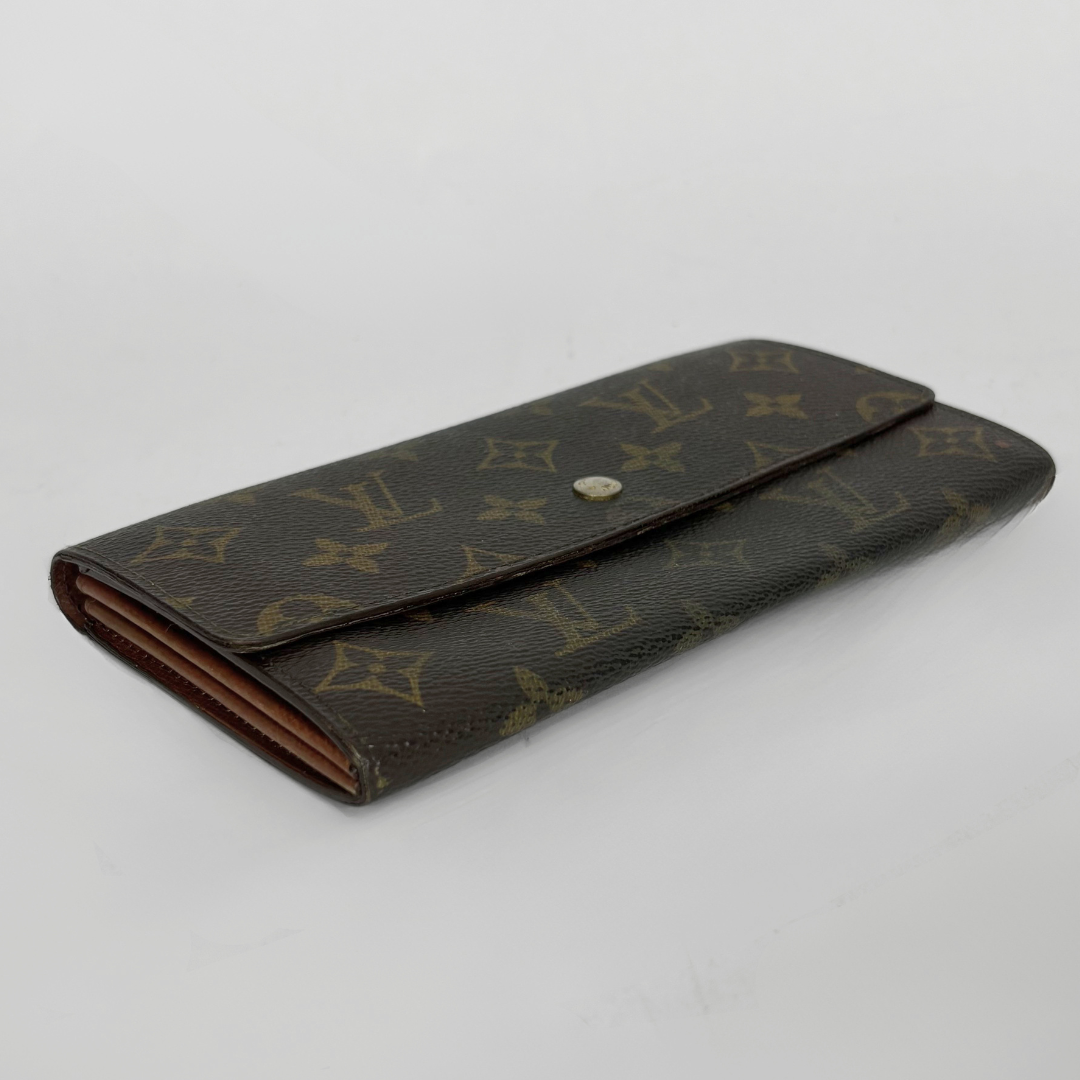 Brown wallet with gold monogram pattern on a light gray background