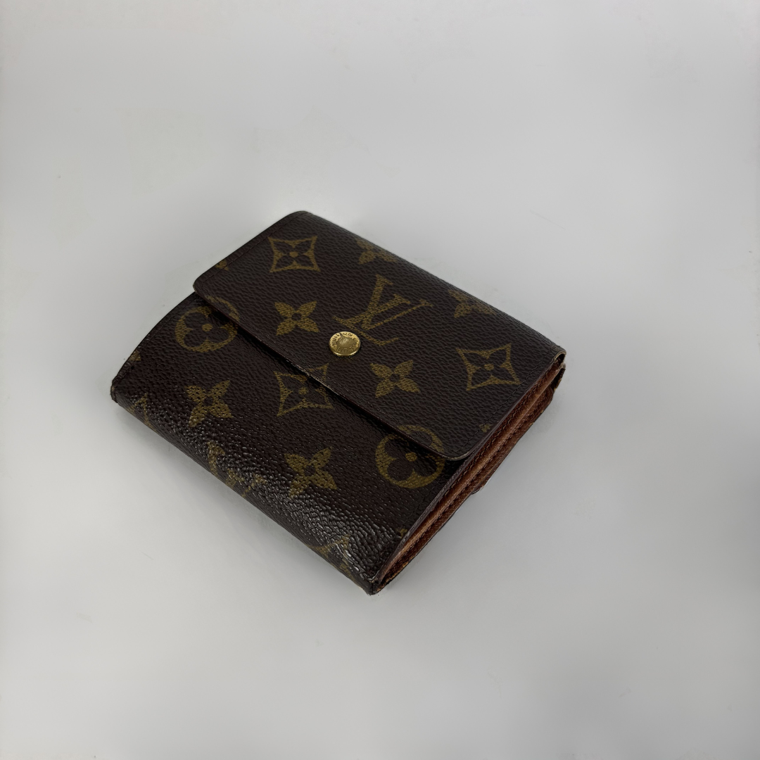 A Louis Vuitton monogram bifold wallet in dark brown coated canvas with gold-tone hardware, photographed on a light gray background.