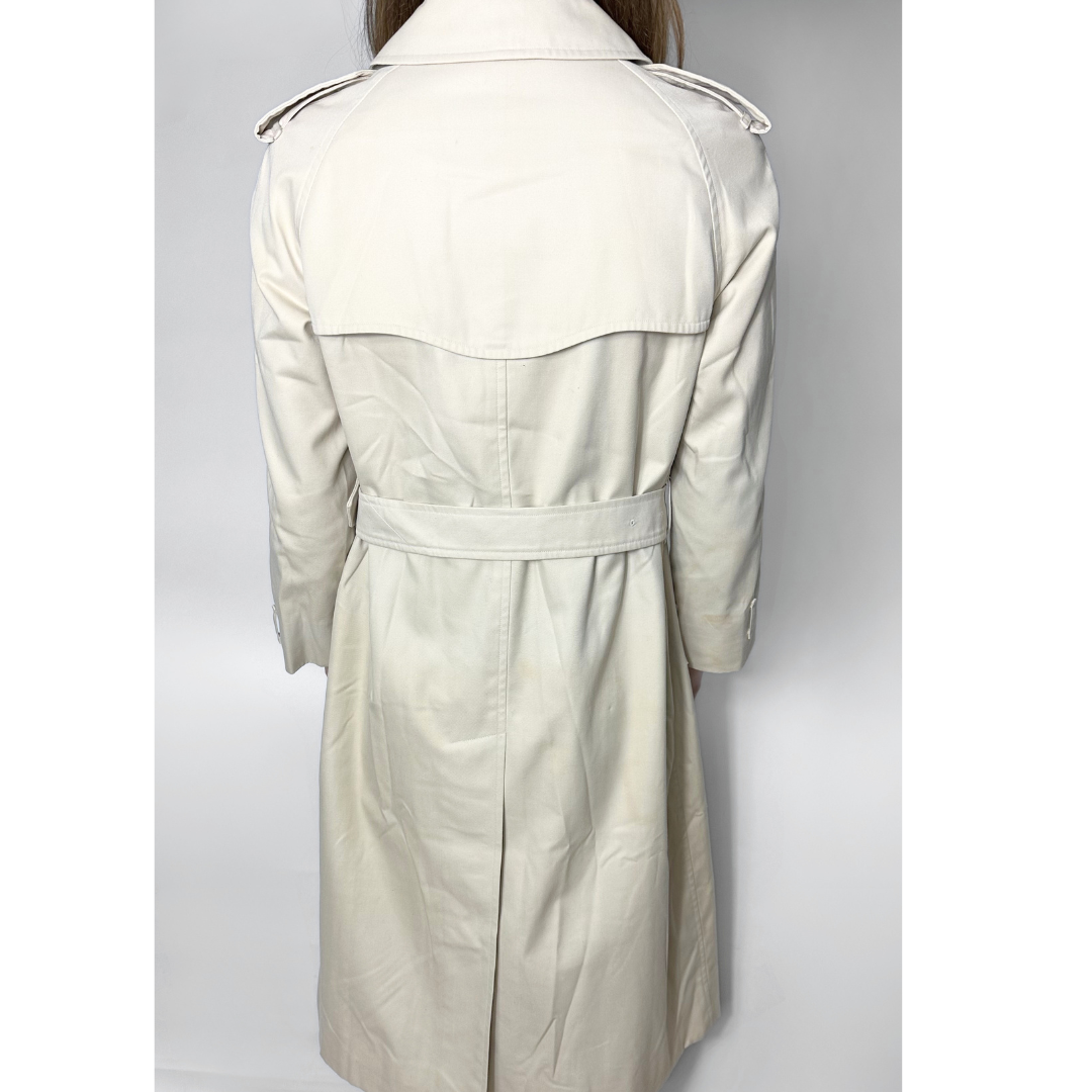 Beige trench coat on a mannequin against a gray background