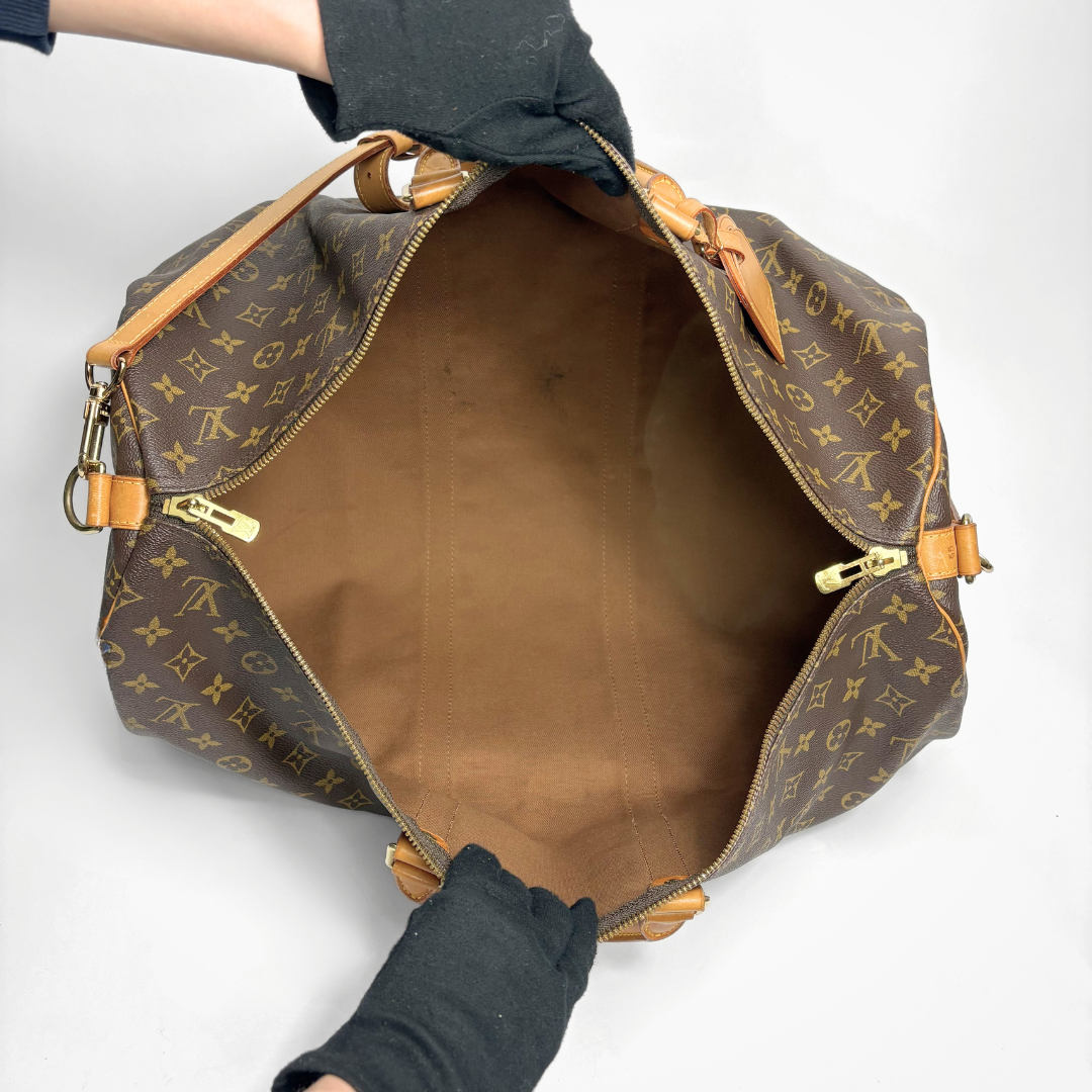 Brown monogram duffel bag with tan leather straps on a white background