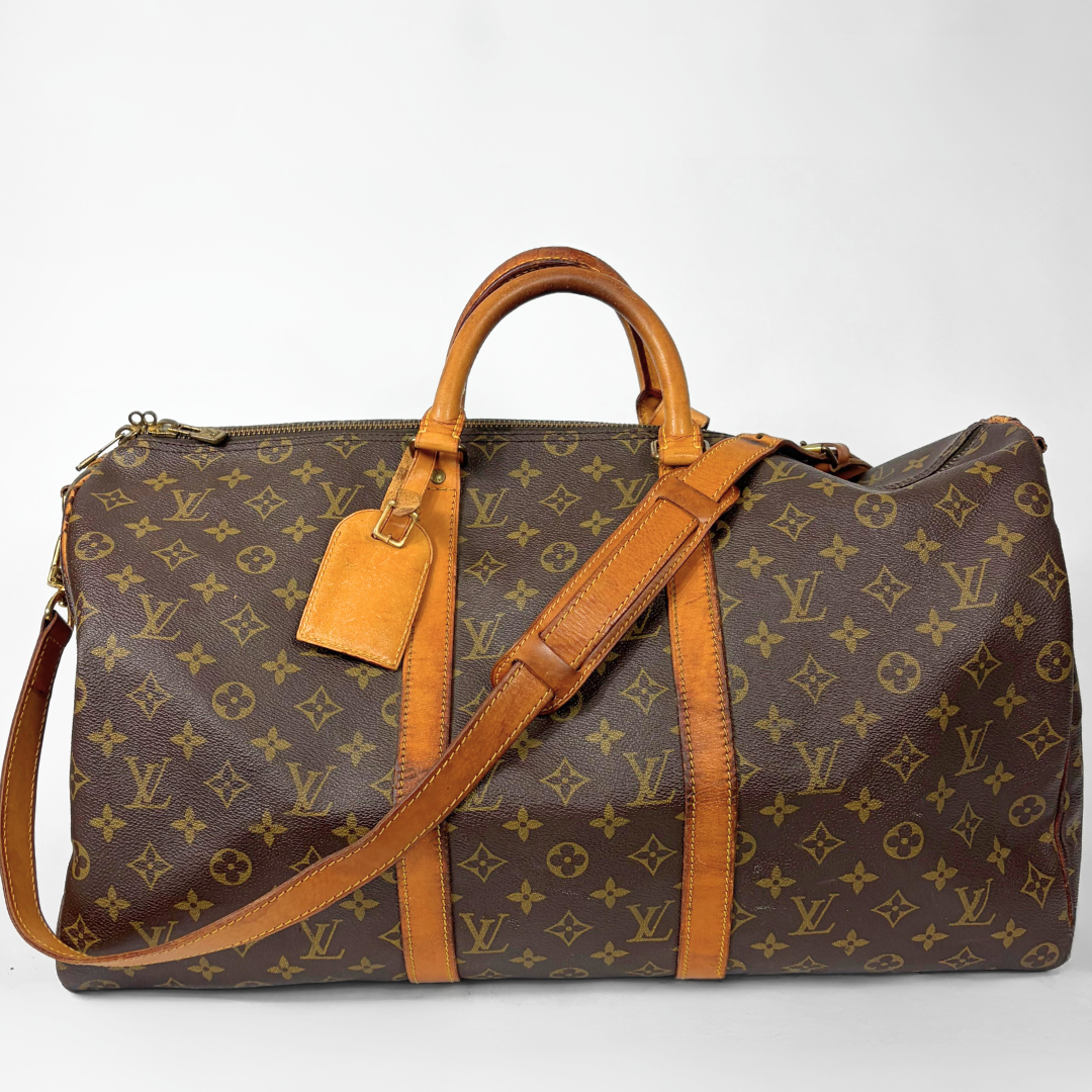 Reisetasche mit braunem Monogrammmuster, hellbraunen Ledergriffen und -riemen auf weißem Hintergrund