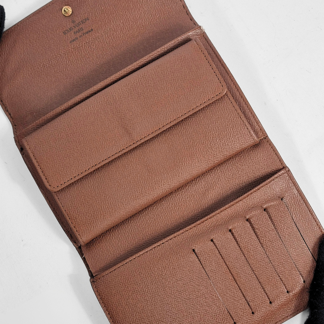Cartera de piel marrón con múltiples ranuras para tarjetas sobre fondo blanco.