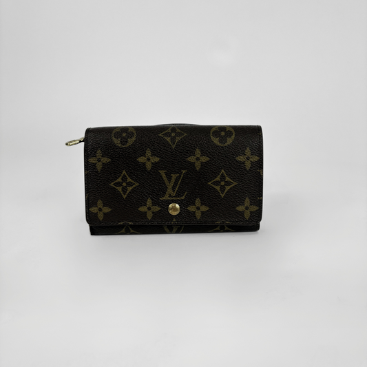 A Louis Vuitton monogram canvas wallet in black with gold-tone hardware, photographed against a plain light gray background.