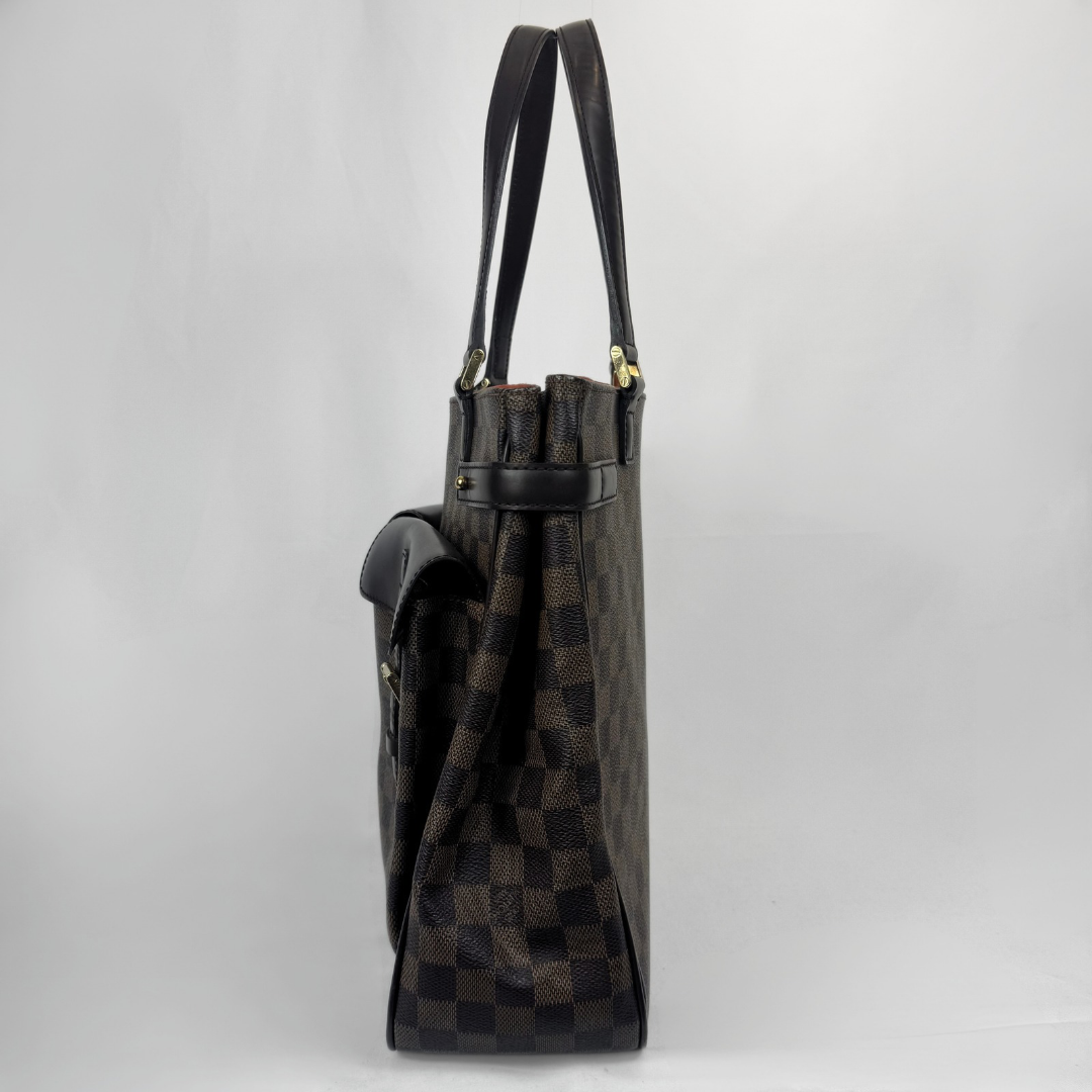 A Louis Vuitton tote bag in Damier Ebene canvas, shown from a side profile view against a light gray background. The bag features the brand's signature dark brown and black checkerboard pattern with dark brown leather trim and gold-tone hardware.