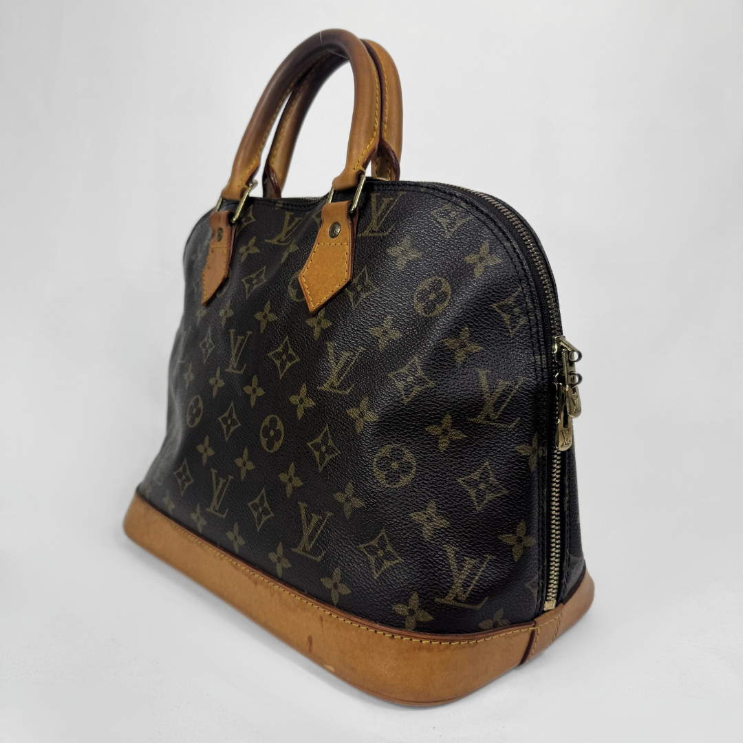 Louis Vuitton monogram canvas dome handbag with tan leather handles and base, photographed on a light gray studio background.