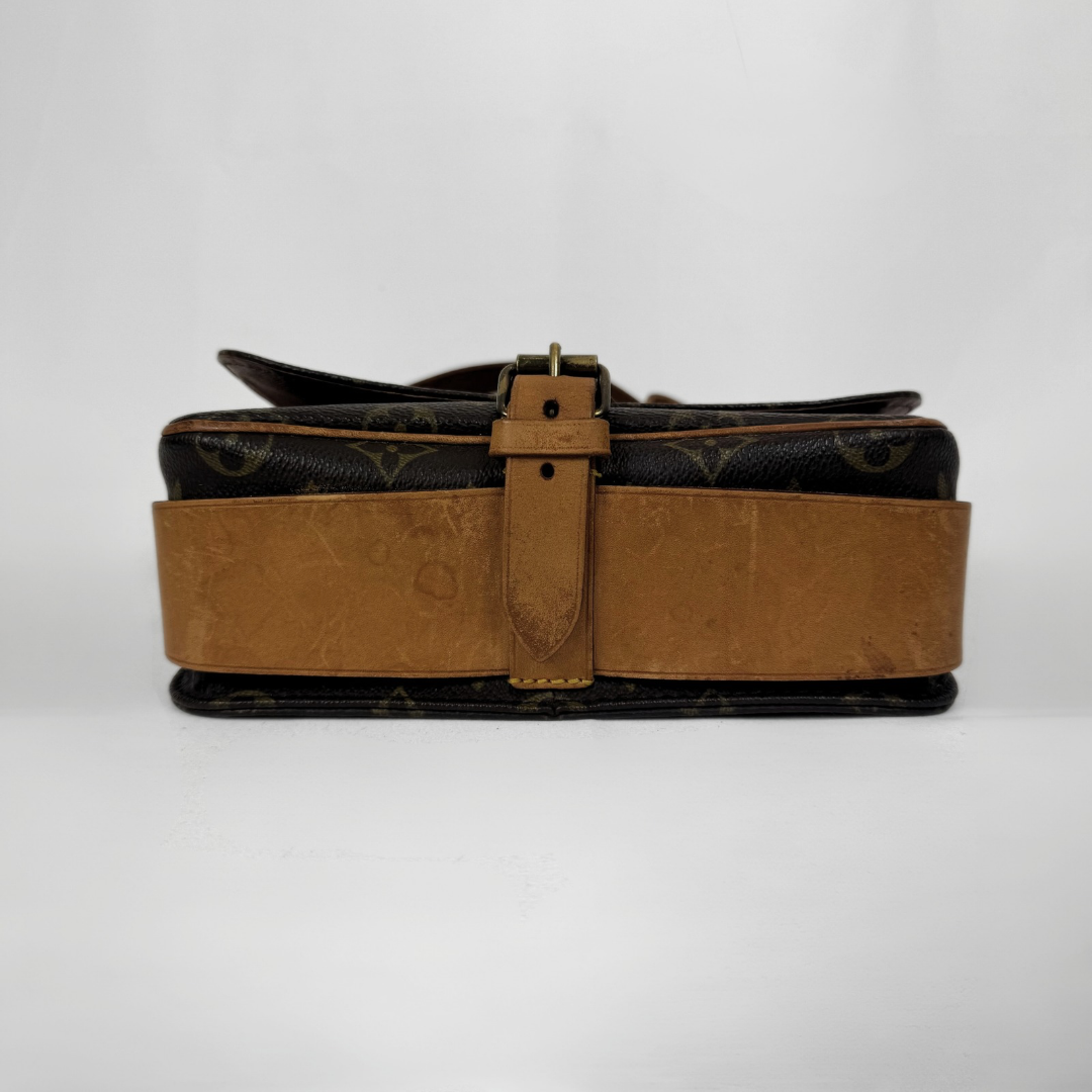 A Louis Vuitton monogram canvas shoulder bag with a wide tan leather strap and a central buckle strap, photographed against a plain white background.