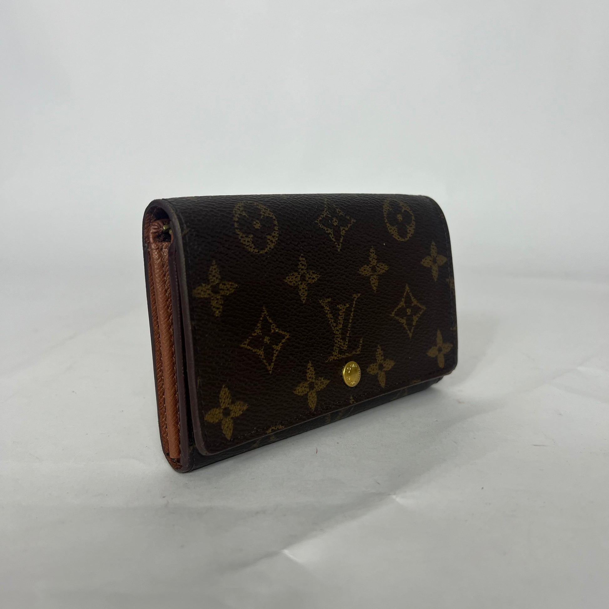 Designer-lompakko, jossa monogrammikuvio valkoisella taustalla
