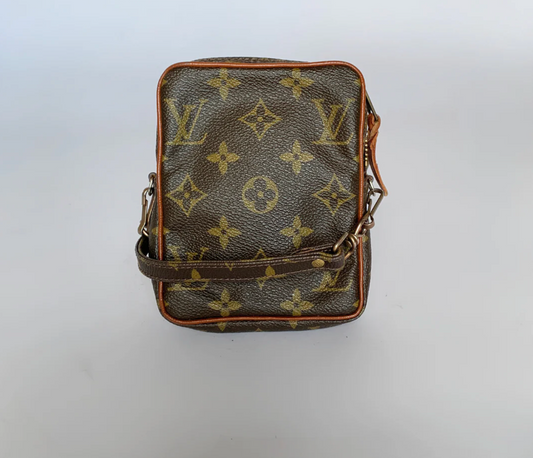 Sort lædertaske med brunt monogrammønster på en hvid baggrund